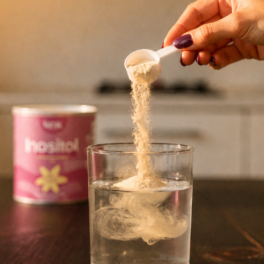 Scoop de Tanik Inositol disolviéndose en un vaso de agua junto a la lata